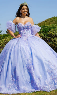 A woman wearing the Quinceanera Ball Gown 8115J with floral details, a strapless sweetheart neckline, removable puff sleeves, and a crown stands outside on a sunny day, smiling.