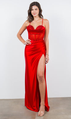 Wearing the Lace-Up Long Prom Dress (Cinderella Couture 8116J), a woman poses confidently in a bright red gown featuring a fitted corset-style bodice, high slit, thin straps, and clear heels against a plain backdrop.