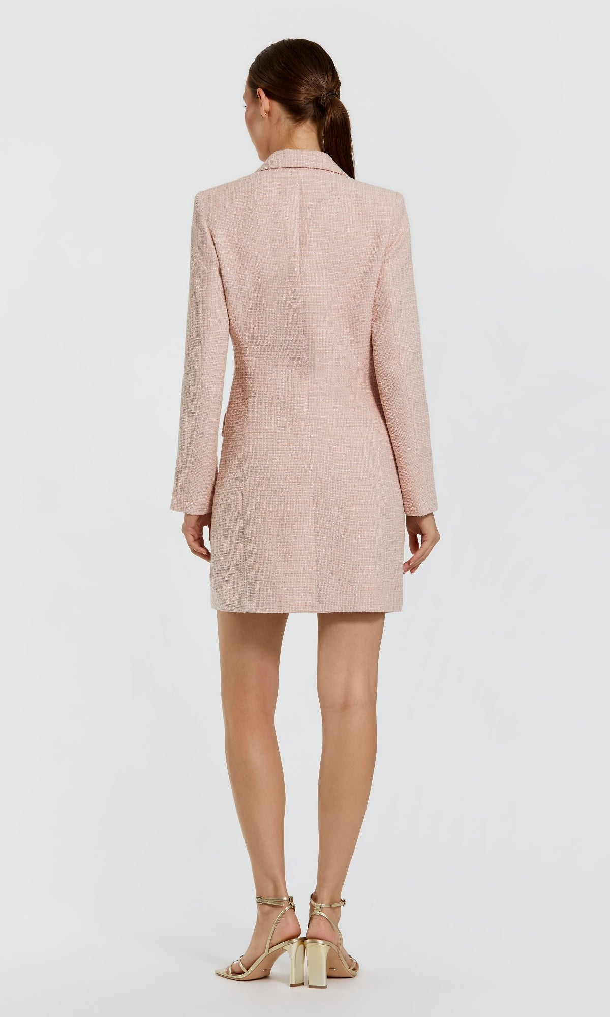 A woman stands facing away, wearing the Short Pink Wedding Guest Dress: Mac Duggal 81198 and beige heeled sandals against a plain white background.