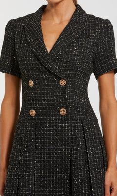A person wears the Mac Duggal 81200 Tweed-Blazer Short Party Dress—black tweed, short sleeves, double-breasted with gold buttons—making it ideal for any semi-formal occasion.
