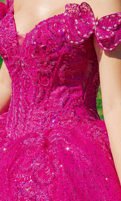 Model wearing the Quinceanera Ball Gown 8120J, featuring a bright pink hue, off-the-shoulder sleeves, intricate beadwork and embroidery, sparkly embellishments, and a beautiful butterfly back detail.
