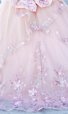 The Quinceanera Ball Gown 8125J features pink tulle, delicate floral embroidery, sequins in pastel pink, lavender, silver, and an elegant corset lace-up bodice.