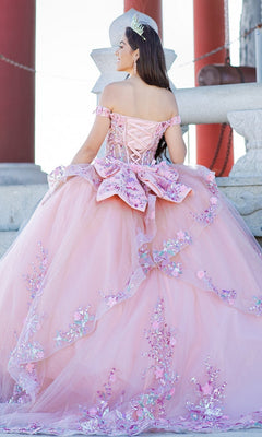 A young woman wearing the Quinceanera Ball Gown 8125J with a corset lace-up bodice and floral decorations stands on stone steps, tiara in place, facing away from the camera.