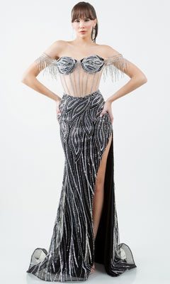 A woman is wearing the Cinderella Couture 8147J, a glamorous long beaded prom dress with an off-the-shoulder neckline, silver embellishments, sheer bodice, beaded fringe sleeves, and a high side slit.