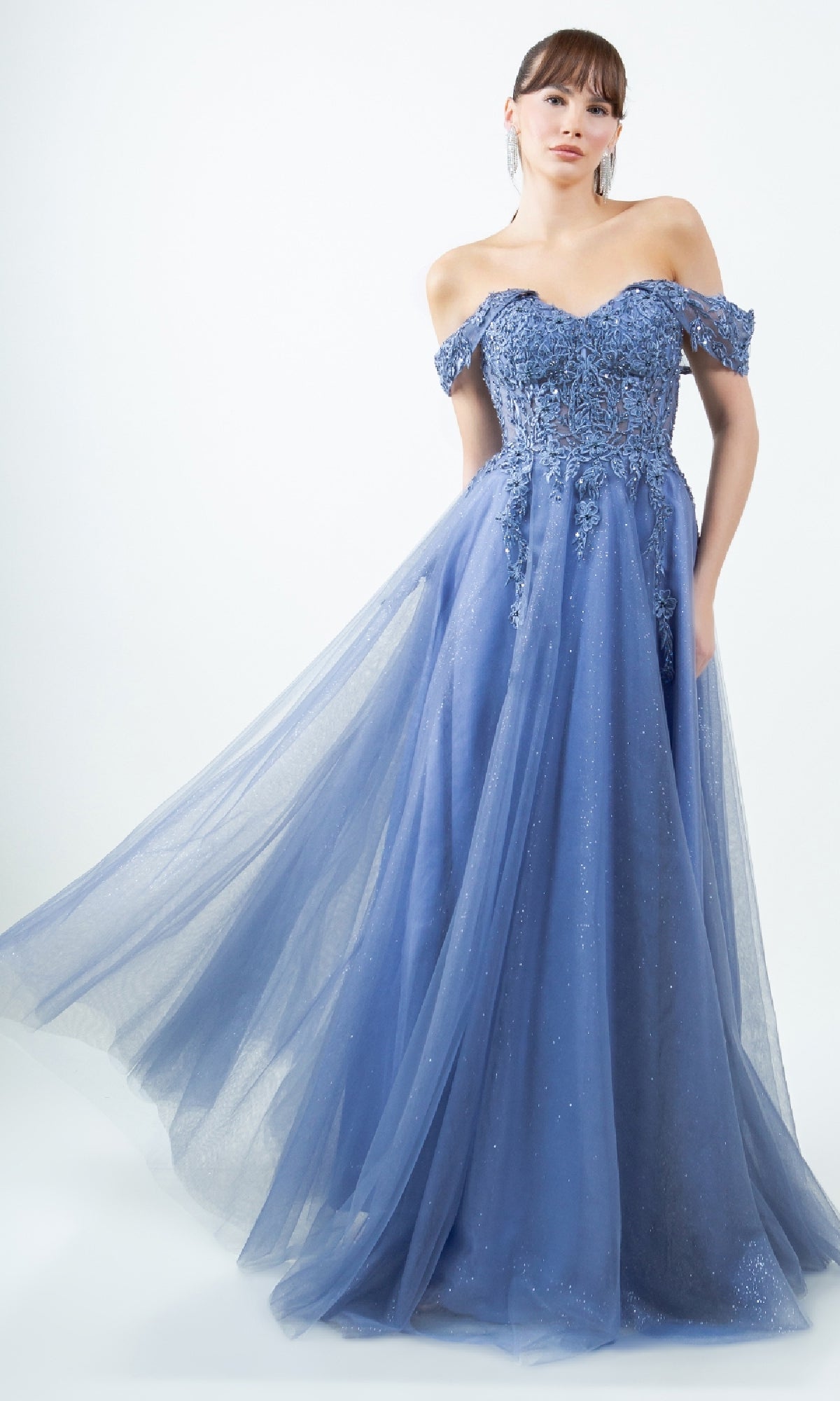 A woman wears the Cinderella Couture 8152J long prom ball gown, featuring an off-the-shoulder embroidered bodice and a flowing tulle skirt, standing against a plain light background.