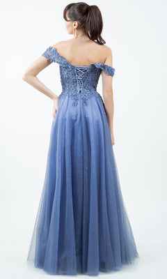 Woman in the Cinderella Couture 8152J long prom ball gown with an off-the-shoulder lace-up back and glittery tulle skirt, standing against a plain light background, facing away from the camera.