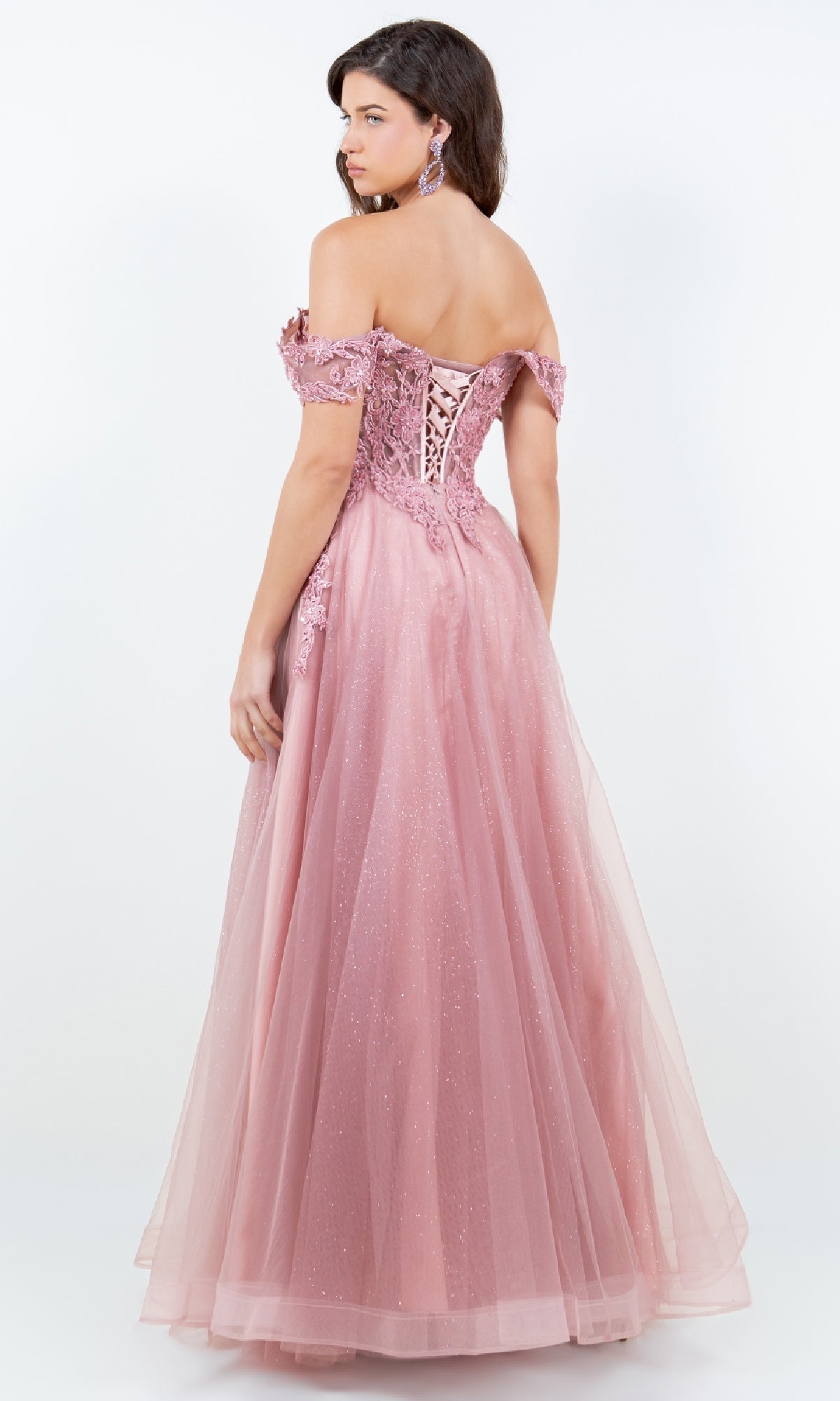 A woman in the Cinderella Couture 8152J long prom ball gown, featuring an off-the-shoulder lace-up back and flowing pink tulle skirt, stands against a plain white background for a timeless A-line silhouette.