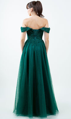 A woman stands facing away from the camera in the Cinderella Couture 8152J—a floor-length green off-the-shoulder prom ball gown with a lace-up back, subtle glitter, and embroidered-lace accents.