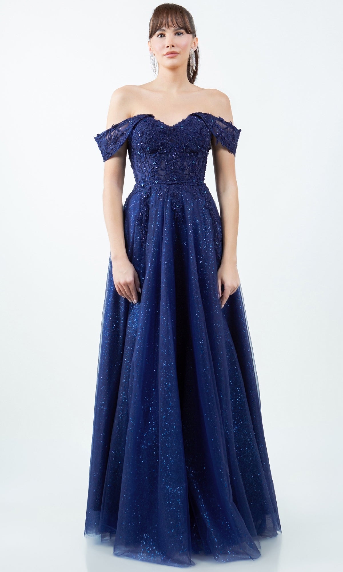 A woman wears the Cinderella Couture 8152J, a long navy blue prom ball gown with an off-the-shoulder fitted bodice and full sparkly skirt, standing against a plain white background.