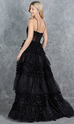 Woman in a sleeveless, floor-length Cinderella Couture 8163J black glitter prom ball gown with ruffled skirt and beaded corset bodice, standing sideways before a gray textured background.