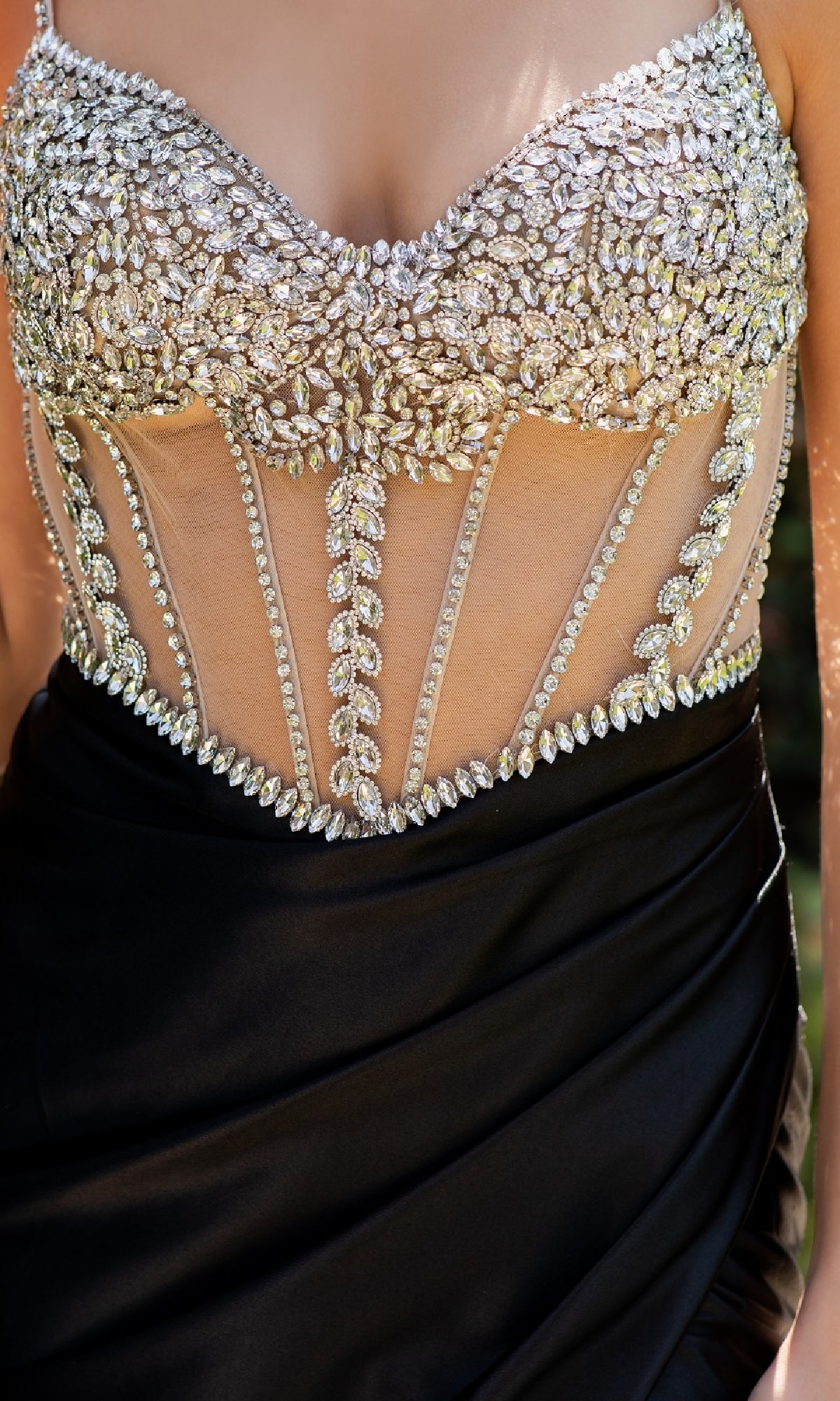 A close-up of a person wearing the Beaded-Bodice Prom Gown: Cinderella Couture 8171J, featuring a sheer bodice adorned with silver rhinestones and intricate black beadwork.