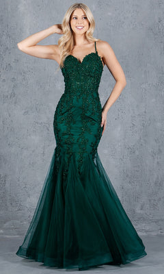 A woman models the Lace-Up Long Prom Dress: Cinderella Couture 8175J, a fitted emerald green mermaid gown with beaded accents and thin straps, standing before a gray textured backdrop.