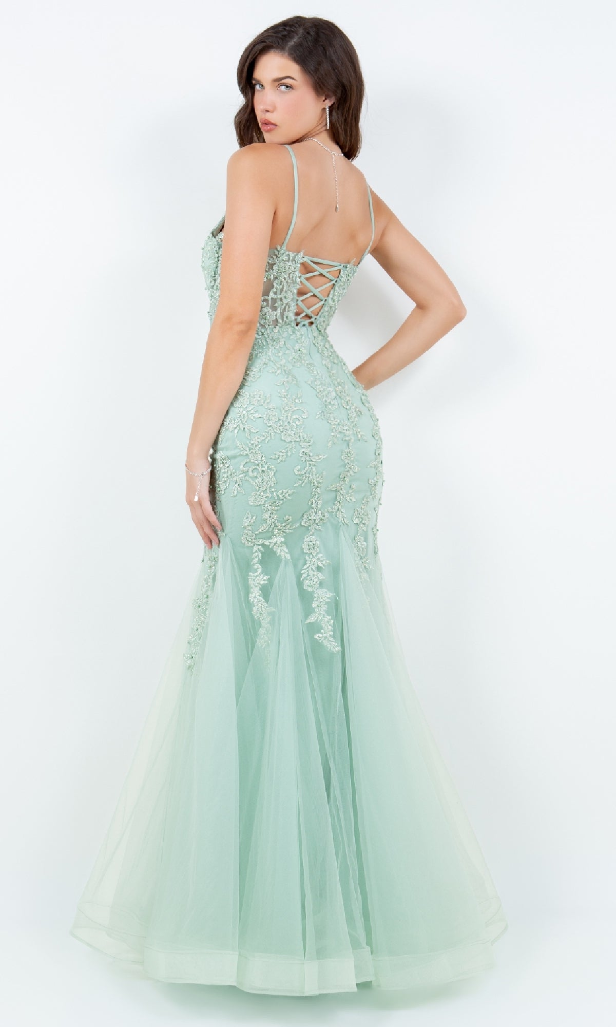 A woman models the Cinderella Couture 8175J, a light green, floor-length lace-up mermaid prom dress with beaded lace applique, posing with her back to the camera against a plain white background.