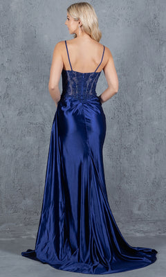 A blonde woman stands against a gray textured background, shown from the back, wearing the floor-length Long Corset Prom Dress: Cinderella Couture 8177J in deep blue satin with thin straps and a fitted bodice.