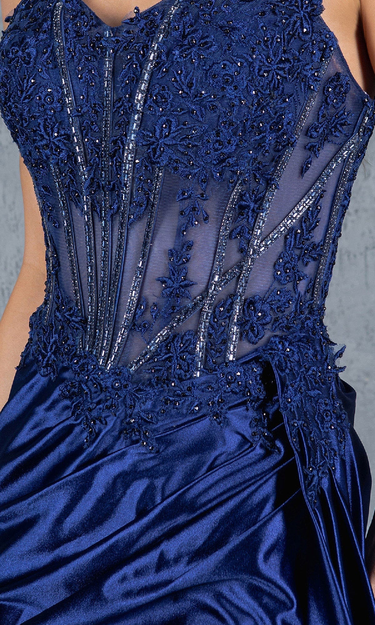A close-up of the Cinderella Couture 8177J, a navy blue long corset prom dress with a beaded bodice, intricate floral embroidery, and a smooth satin skirt.