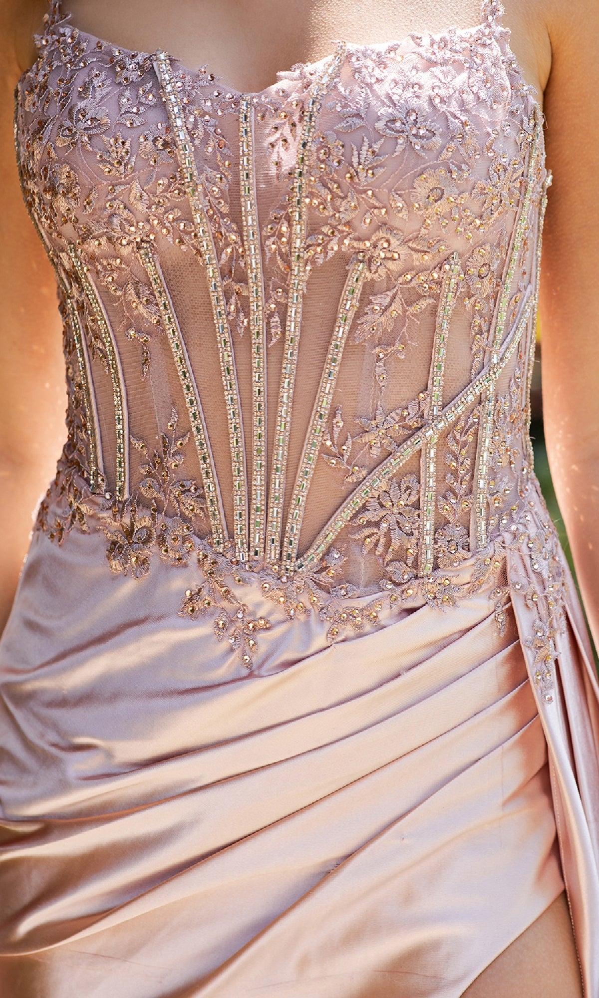Close-up of a person wearing the Long Corset Prom Dress: Cinderella Couture 8177J, a strapless blush gown with a beaded corset bodice, intricate floral embroidery, and sheer panels.
