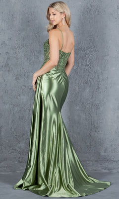 A woman in the Cinderella Couture 8177J long corset prom dress, featuring a green floor-length skirt and beaded bodice, stands with her back to the viewer and head turned to the side against a textured gray background.