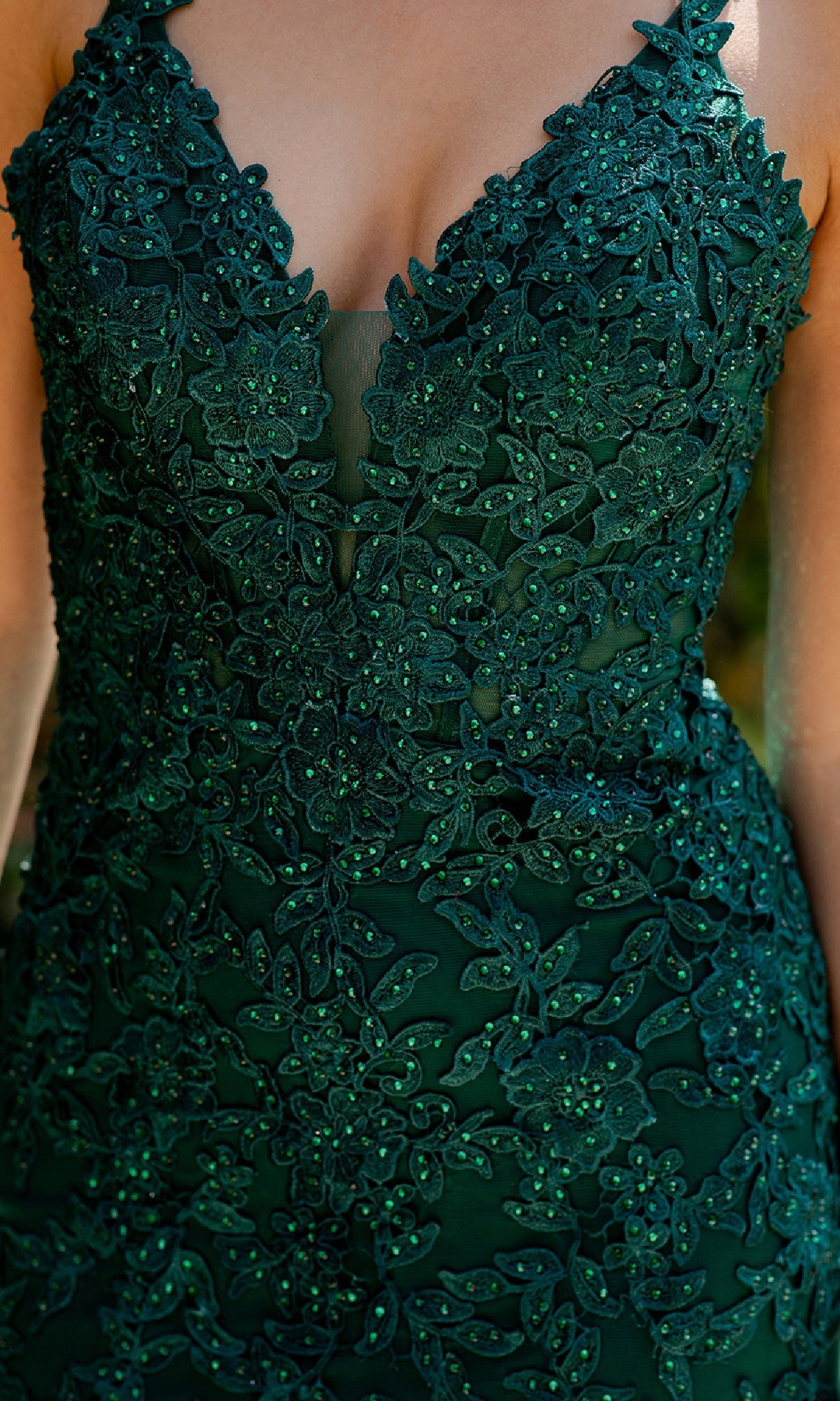 A close-up of a person wearing the Cinderella Couture 8178J Beaded Long Prom Dress in dark green, featuring floral lace patterns and delicate beaded embroidery.