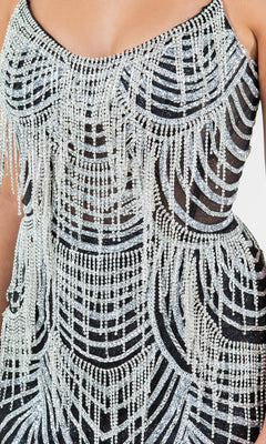 A close-up of the Beaded Long Prom Dress Cinderella Couture 8192J: a black evening gown with sheer panels, featuring intricate silver bead and crystal fringe in geometric patterns.