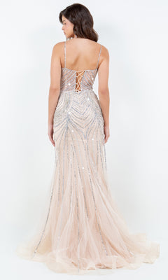 A woman wears the Beaded Long Prom Dress: Cinderella Couture 8192J, featuring a lace-up back, thin straps, and silver sequin embellishments over nude tulle—an elegant choice for any special occasion.