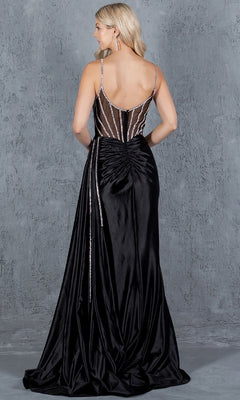 A woman in the Side-Sash Long Prom Gown (Cinderella Couture 8219J), a floor-length black satin dress with a ruched back and beaded sheer bodice, stands against a textured gray background, facing away from the camera.