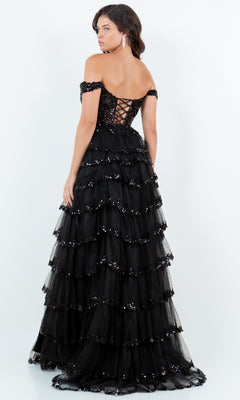 A woman in the Cinderella Couture 8228J Ruffle Prom Ball Gown with layered ruffles, sequin embroidery, and a lace-up back stands facing away from the camera.