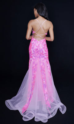 A woman faces away in a pink Nina Canacci 8236 sequin mermaid gown with tulle and crisscross straps, standing against a black background.