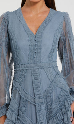 A woman wearing the Mac Duggal 8247 Blue Midi Wedding Guest Dress, featuring a light blue hue, V-neckline, decorative buttons, ruffled and sheer textured details, and elegant long sleeves.