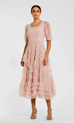 A woman wears the Mac Duggal 8248 Midi Wedding Guest Dress in light pink, featuring ruffles, a midi skirt, and short puff sleeves, paired with silver high-heeled sandals against a plain white background.