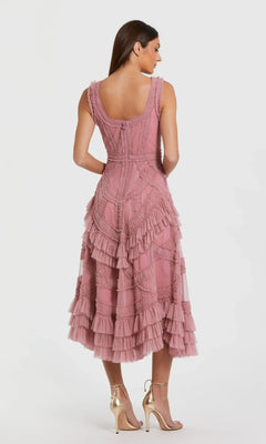 A woman faces away, wearing the Mac Duggal 8250 midi wedding guest dress with micro ruffle details and gold high heels, set against a plain white background.