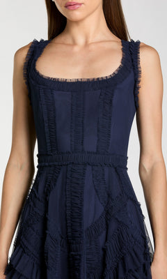 A woman models the Ruffled Midi Wedding Guest Dress: Mac Duggal 8250 in navy blue, featuring ruffle detailing and a scoop neckline, shown from shoulders to mid-thigh.