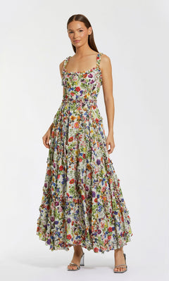 A woman wears the Mac Duggal 8256 Floral Wedding Guest Dress—an ankle-length, sleeveless gown with a fitted bodice and flared A-line skirt—paired with strappy heels against a plain white background.