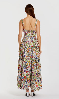 A woman models the Mac Duggal 8256 Floral Wedding Guest Dress—an ankle-length, sleeveless A-line dress with an open back and scoop neckline—facing away from the camera against a white background.