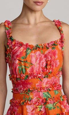 Close-up of a woman wearing the Mac Duggal 8257 Ruffle Short Floral Party Dress in orange with pink floral patterns and ruffled details on the straps, neckline, and waist.