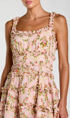 A woman wearing the Mac Duggal 8257 Ruffle Short Floral Party Dress—a pink, sleeveless party dress featuring a ruffled trim and delicate floral pattern.
