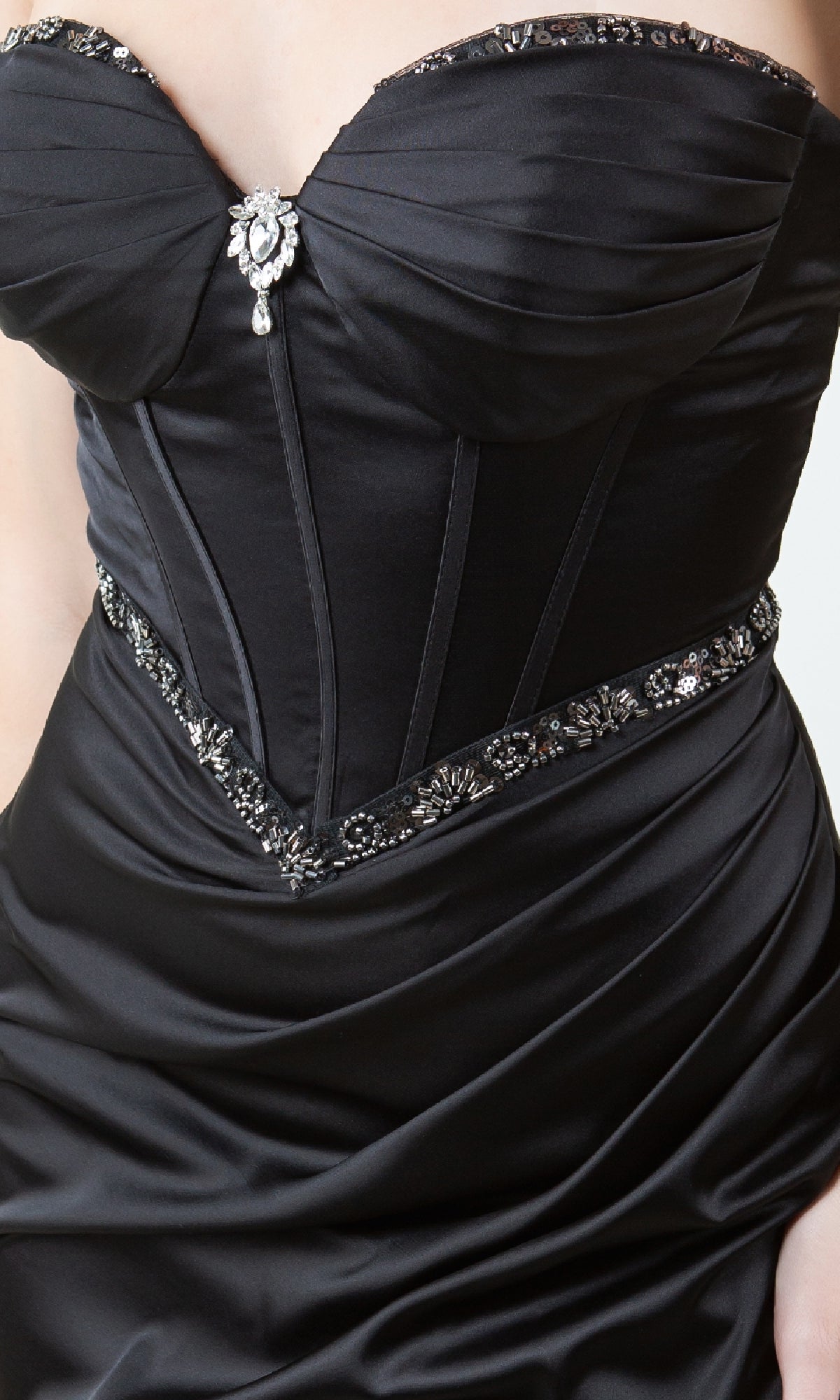 A close-up of a person wearing the Strapless Long Prom Gown: Cinderella Couture 8259J, featuring a corset-style bodice, black satin fabric, beaded trim, and a jeweled brooch at the center.
