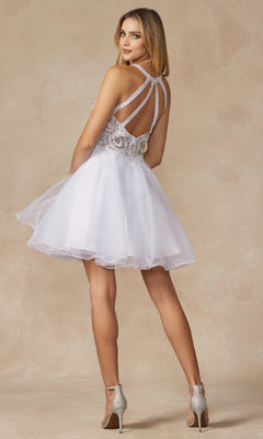 A woman in the Short Hoco Dress: Juliet 826, featuring a lace bodice, multi-strap open back, and an A-line tulle skirt, stands in high heels against a beige background for a dreamy, chic look.
