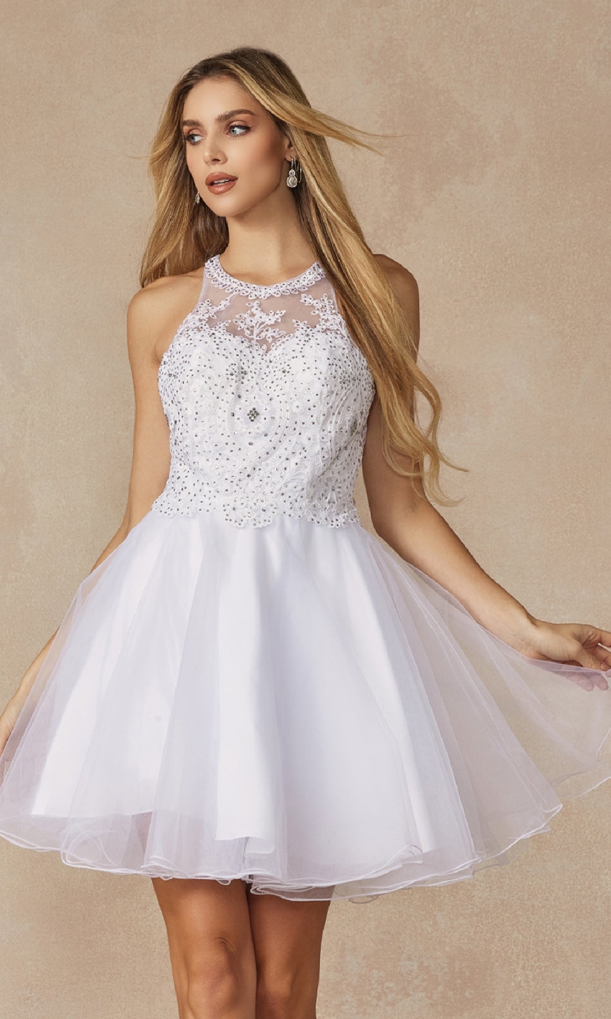 A woman models the Juliet 826 Short Hoco Dress, featuring a sleeveless bodice with rhinestone accents and an a-line tulle skirt, set against a beige background.