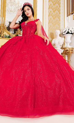 A woman wearing the Quinceanera Dress 8270J by Cinderella Couture in sparkling red stands in an ornate room adorned with gold decor, a chandelier, and a white bust statue in the background. The dress showcases glitter tulle and intricate 3D floral appliques that catch the light beautifully.