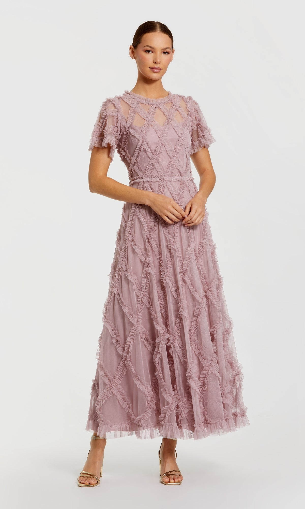 Woman wearing a pink a-line dress with mini ruffles standing in front of a white background