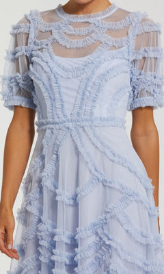A person wearing the Midi Party Dress: Mac Duggal 8288, a light blue A-line midi dress with sheer short sleeves and micro-ruffle detailing, featuring ruffled, textured patterns in both curved and straight designs.