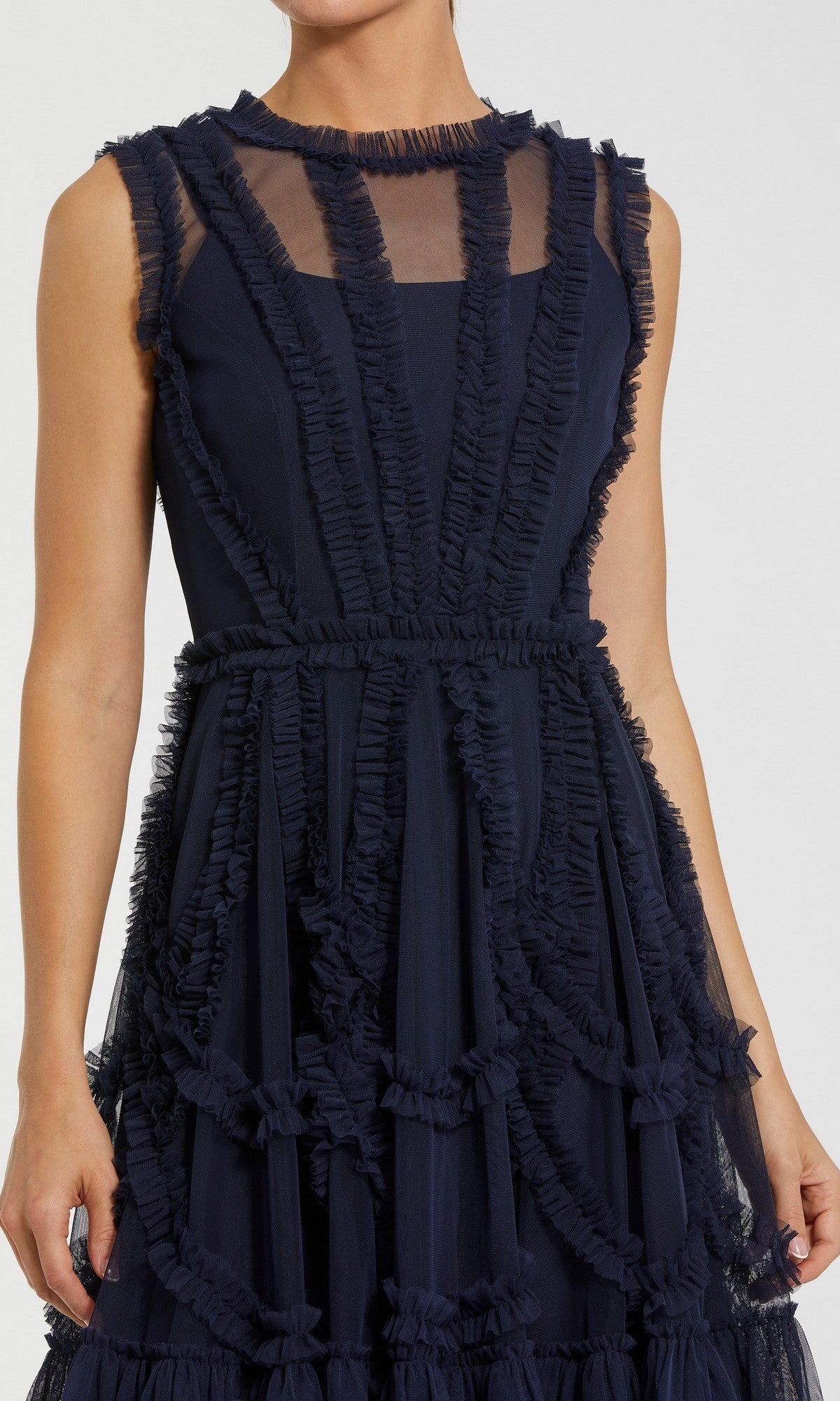 A person wearing the Short Wedding Guest Dress: Mac Duggal 8289—a sleeveless high-neck mini dress with sheer panels and geometric ruffled trim.