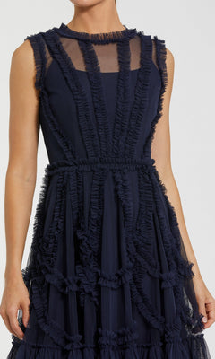 A person wearing the Short Wedding Guest Dress: Mac Duggal 8289—a sleeveless high-neck mini dress with sheer panels and geometric ruffled trim.