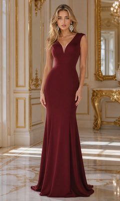 A woman stands in an ornate room wearing the Cap Sleeve Long Jersey Prom Dress 8290 in burgundy. Gold decor and natural light enhance the elegant setting, making this affordable formal dress perfect for any special occasion.