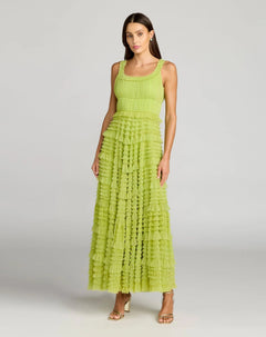 A woman stands against a plain light gray background wearing the Mac Duggal 8292 Tea-Length Party Dress—a sleeveless, lime green A-line tiered maxi with delicate ruffle detailing—paired with gold open-toe heels.