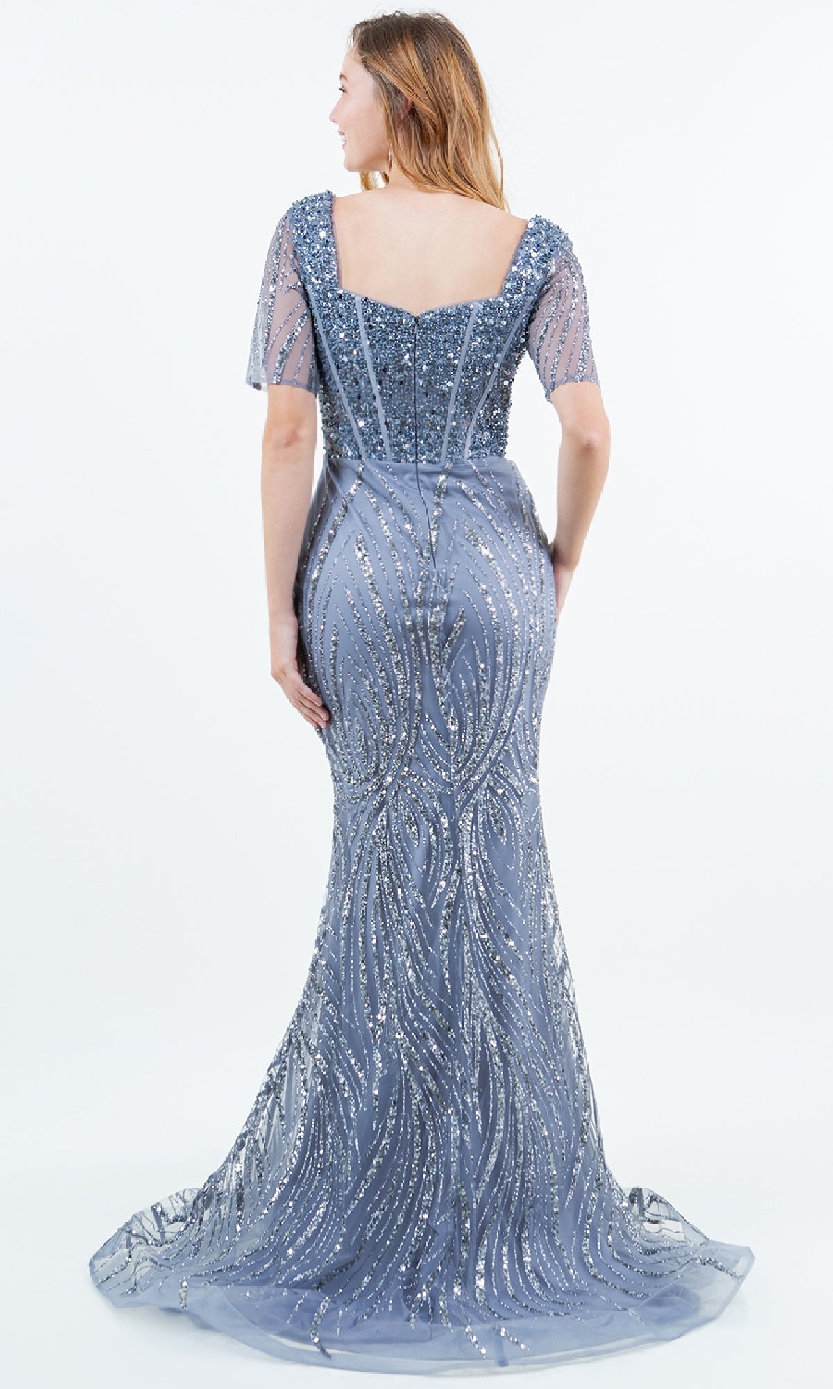 A woman is seen from behind wearing the Cinderella Couture 8293M, a floor-length fitted blue sequin formal gown with short sleeves, a square neckline, and shimmering patterns—an elegant evening dress.