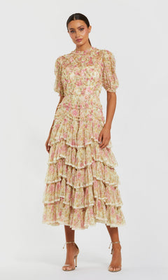 A woman stands against a plain white background wearing the Midi Wedding Guest Dress: Mac Duggal 8295 in Ivory Multi, featuring floral mesh fabric, puff sleeves, ruffle details, and nude high-heeled sandals.