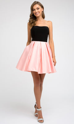 A woman stands facing forward, wearing the Juliet 829 short party dress with a strapless sweetheart neckline, an A-line pink knee-length skirt, and light-colored high heels.