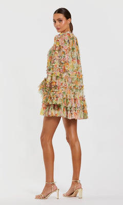 A woman in profile wears the Mac Duggal 8300 Bell-Sleeve Floral Wedding Guest Dress with gold high-heeled sandals, standing against a plain white background.