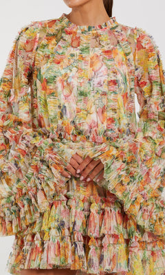 Woman in the Mac Duggal 8300 Bell-Sleeve Floral Wedding Guest Dress, featuring vibrant ruffles and layered textured fabric—a stunning long-sleeve choice for celebrations.